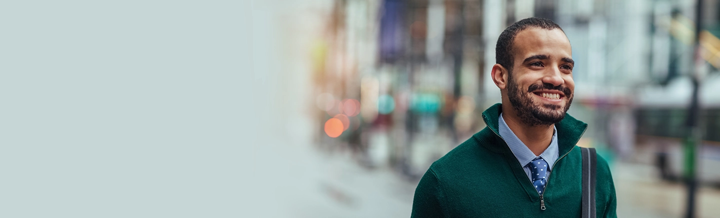 Smiling man wearing a green sweater over a dress shirt, looking confident and approachable.