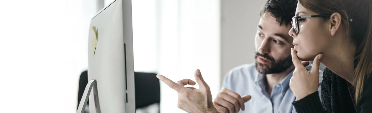 Two professionals collaborating in front of a computer screen during a business meeting in a modern office