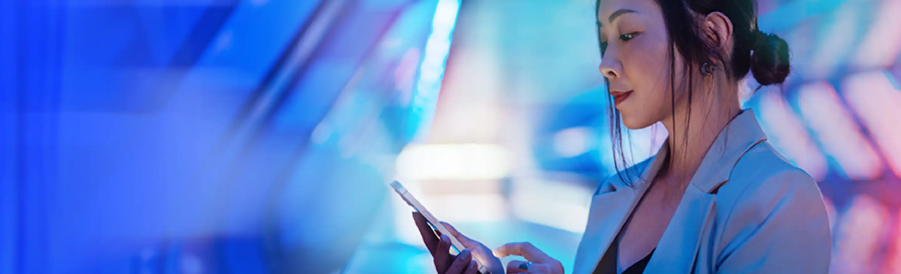 Une femme regarde son téléphone portable sur un fond bleu et rose.